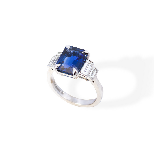 Ring with a sapphire gemstone and diamond accents on a white background